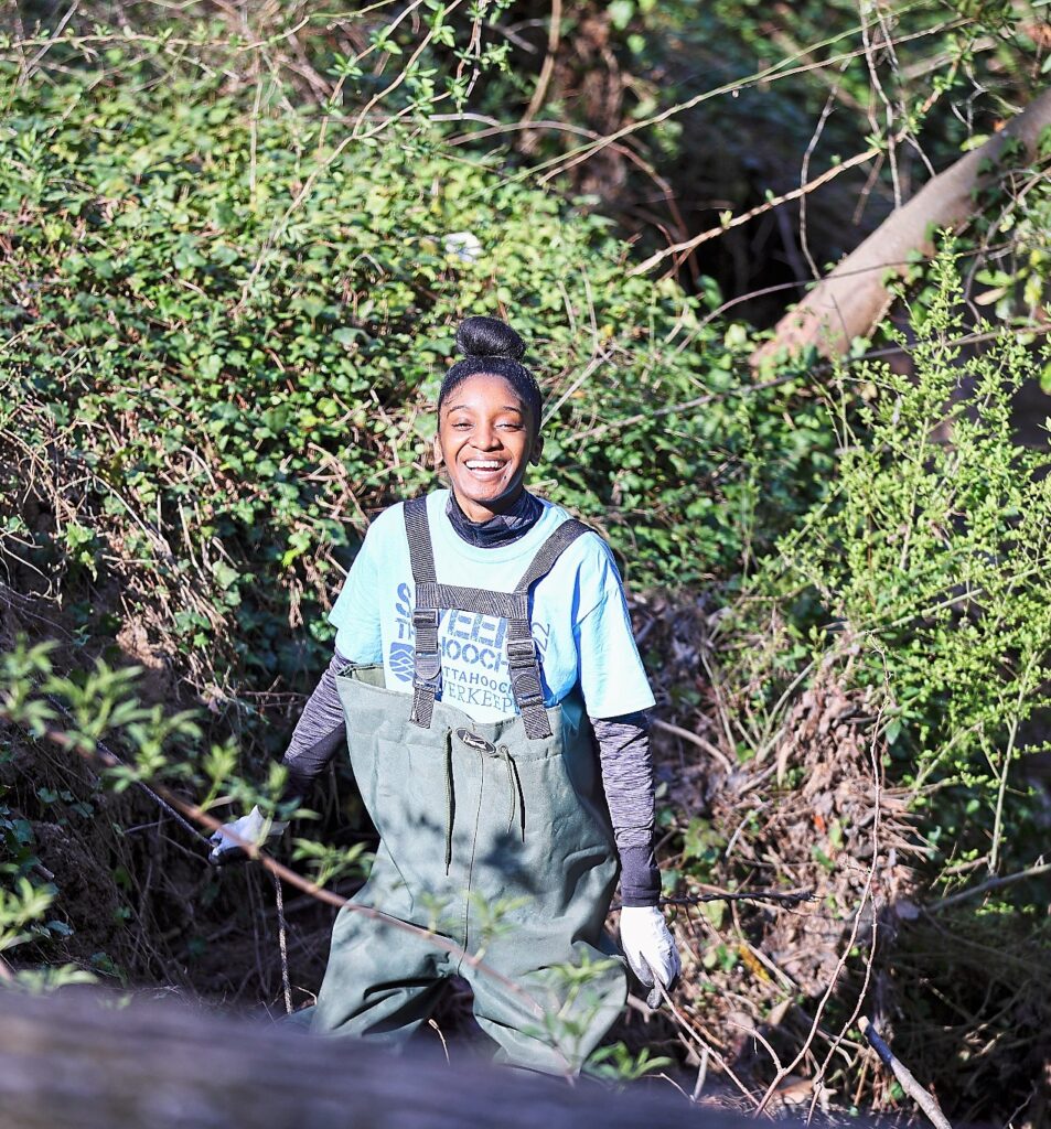 A smiling volunteer wearing waders.