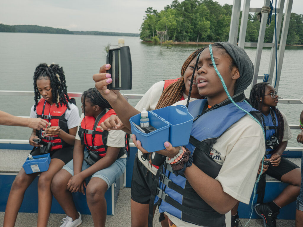 Students wearing life vests aboard the West Point Lake Floating Classroom participate in educational STEM activities.