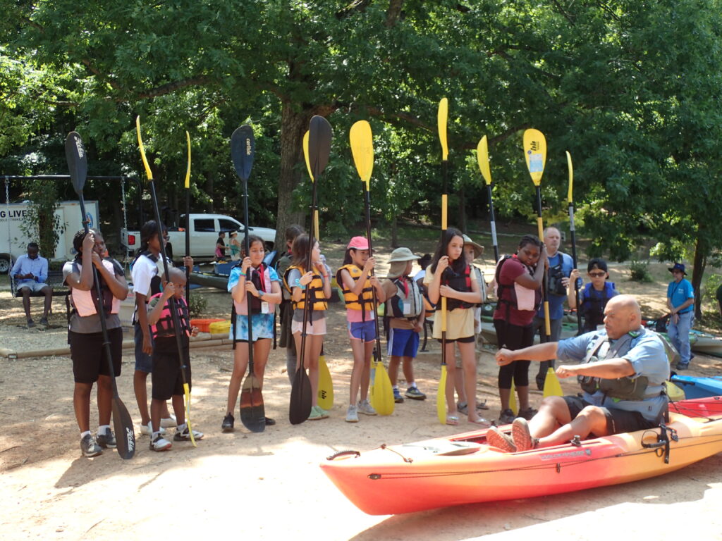 Students hold paddles during a kayaking lesson at a Water Warriors Wander & Wonder event.